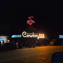 Neon sign reading 'Million Dollar Cowboy Bar' with a red neon cowboy figure above the entrance at night